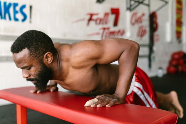 Man performing a controlled bodyweight exercise in a minimalist gym setting.